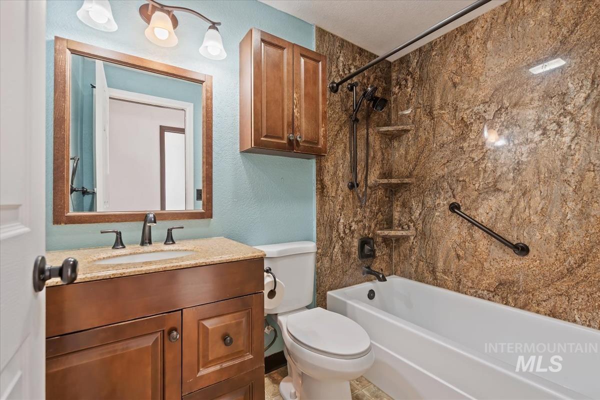 Full bath featuring bathing tub / shower combination, vanity, and a textured wall