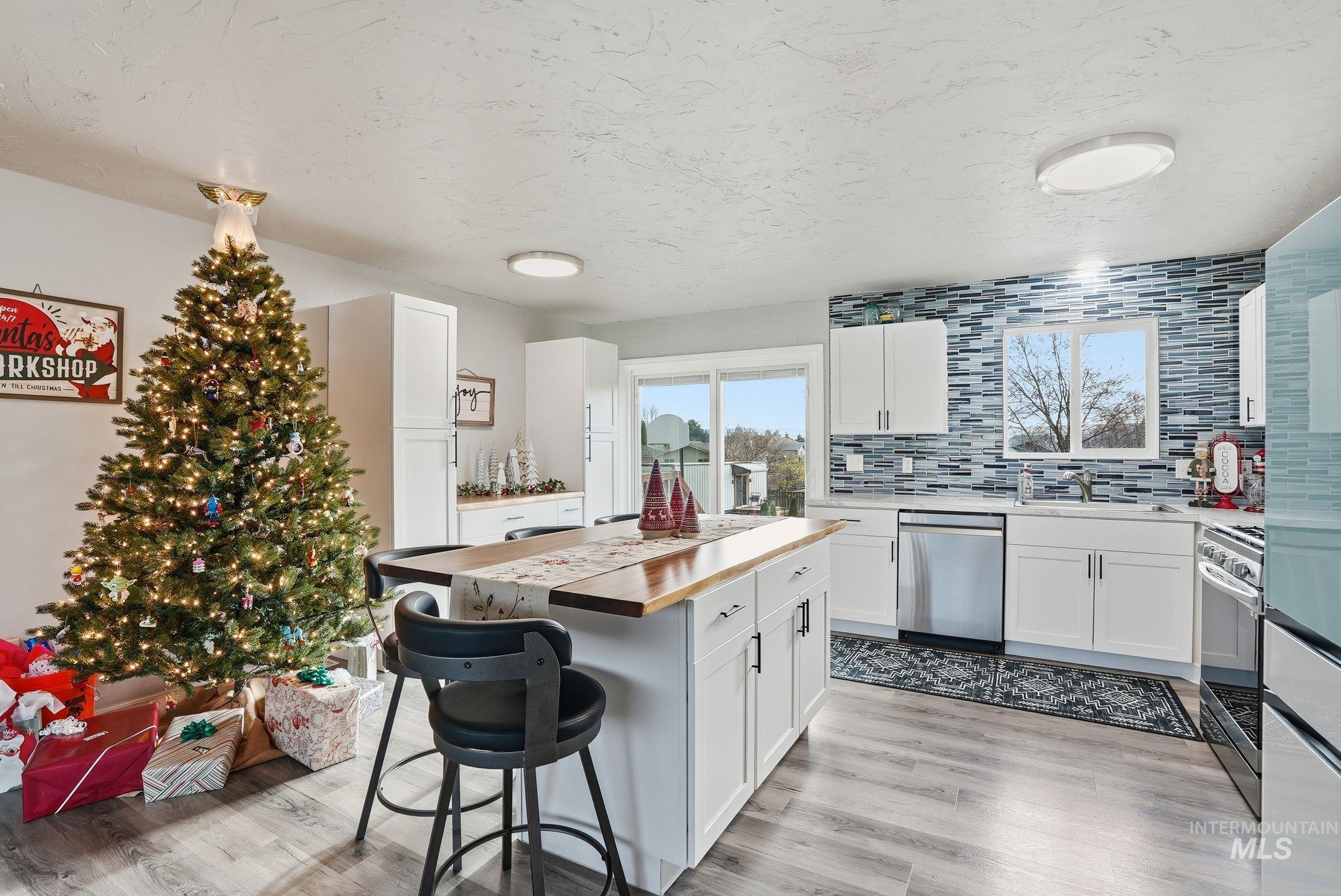 Kitchen with wooden counters, a kitchen breakfast bar, white cabinets, appliances with stainless steel finishes, and a center island