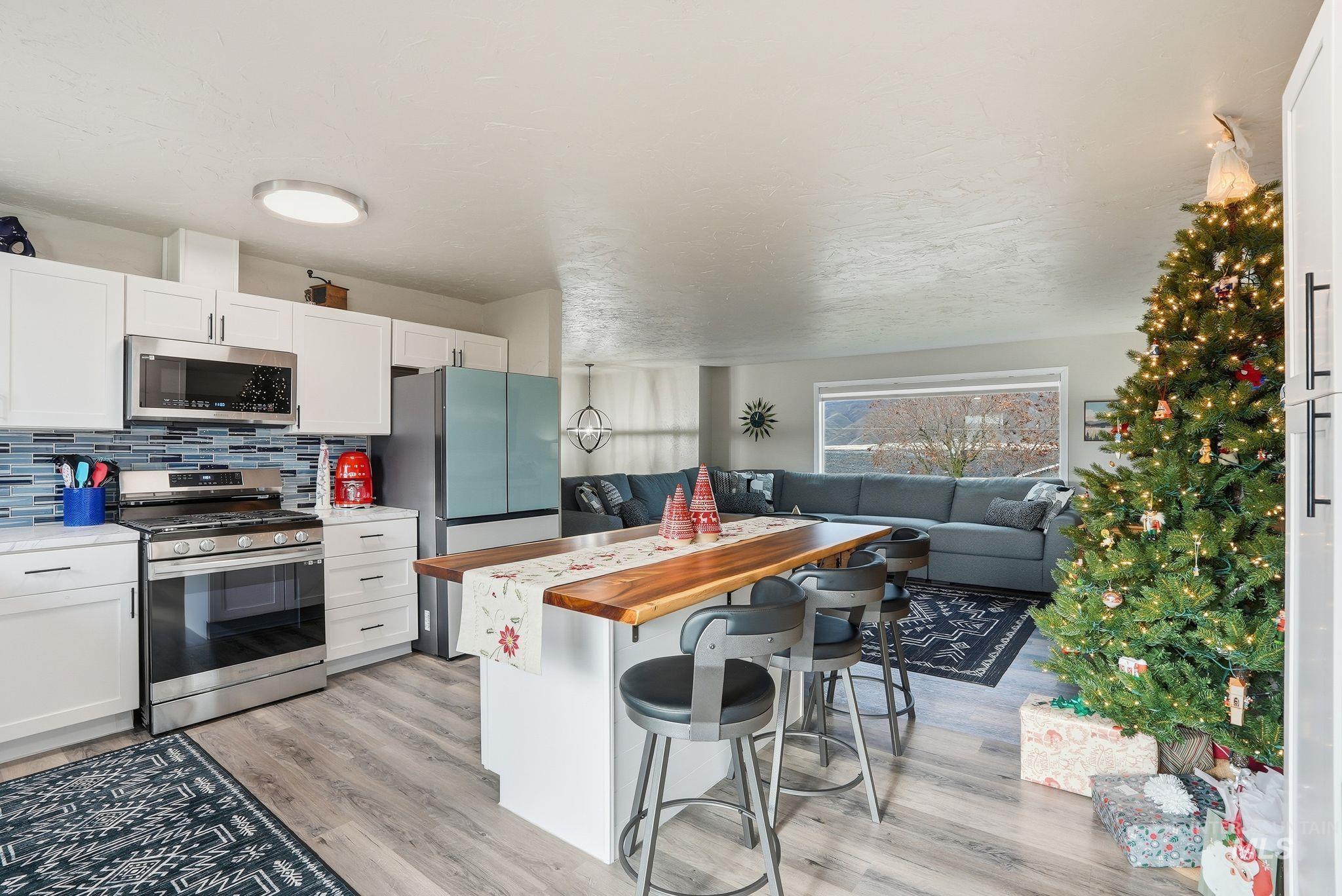 Kitchen with butcher block countertops, stainless steel appliances, a breakfast bar, white cabinets, and backsplash