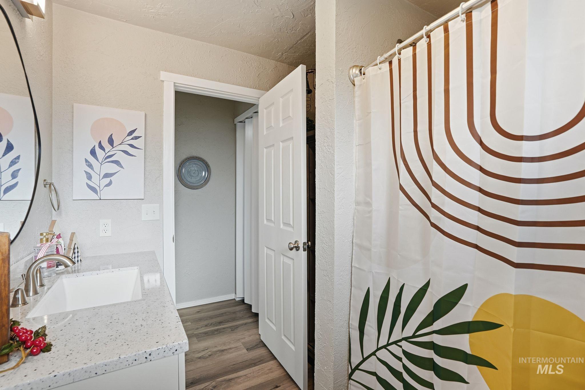 Bathroom featuring vanity, a textured wall, a shower with curtain, and dark wood-style floors