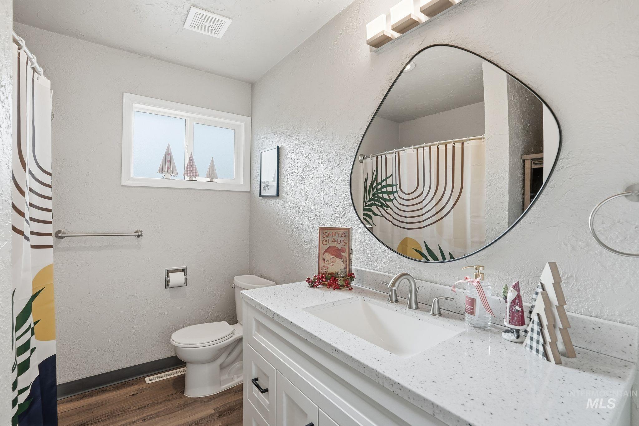 Full bath featuring a textured wall, vanity, dark wood-style flooring, and a shower with curtain