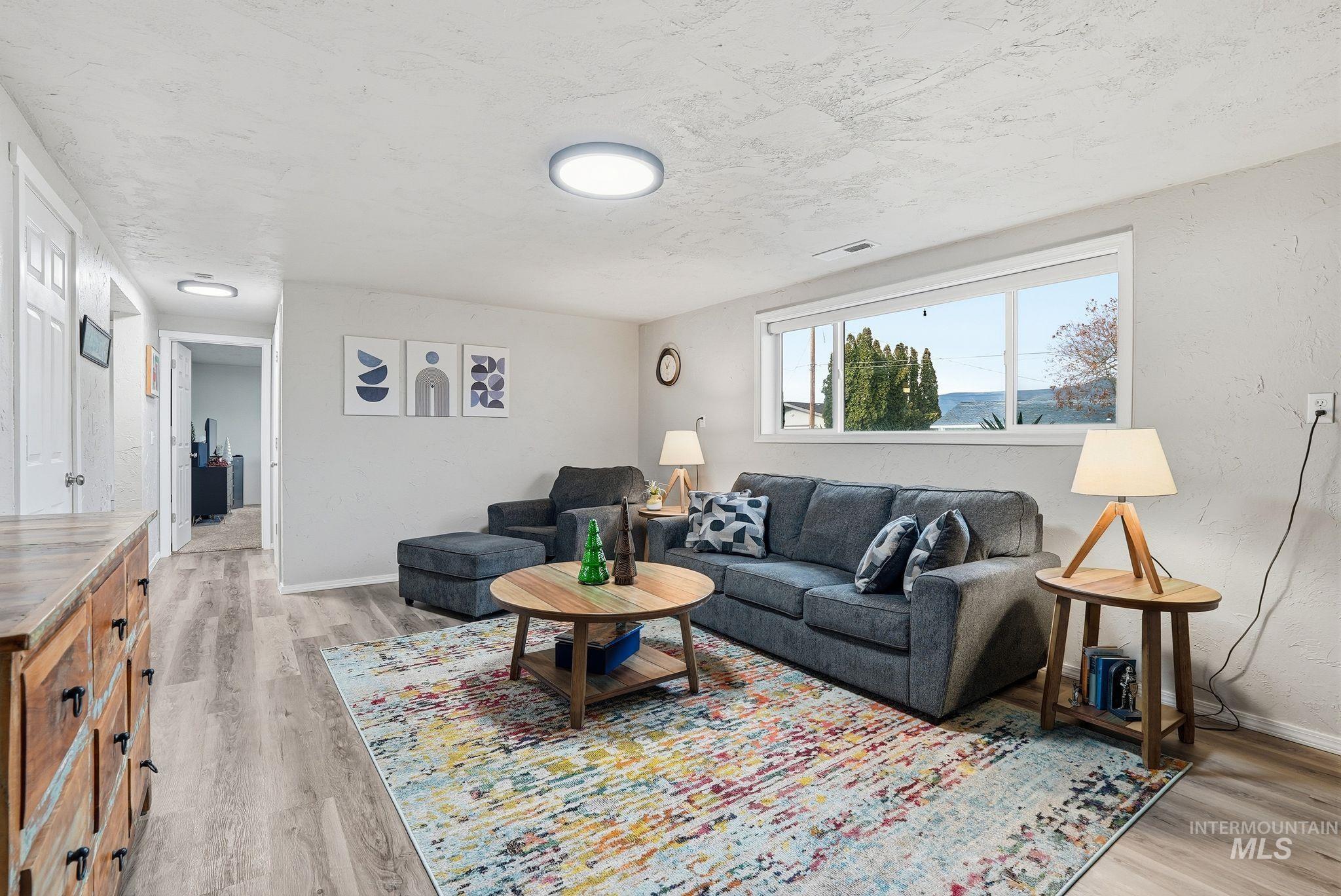 Living room featuring light wood-type flooring and a textured ceiling