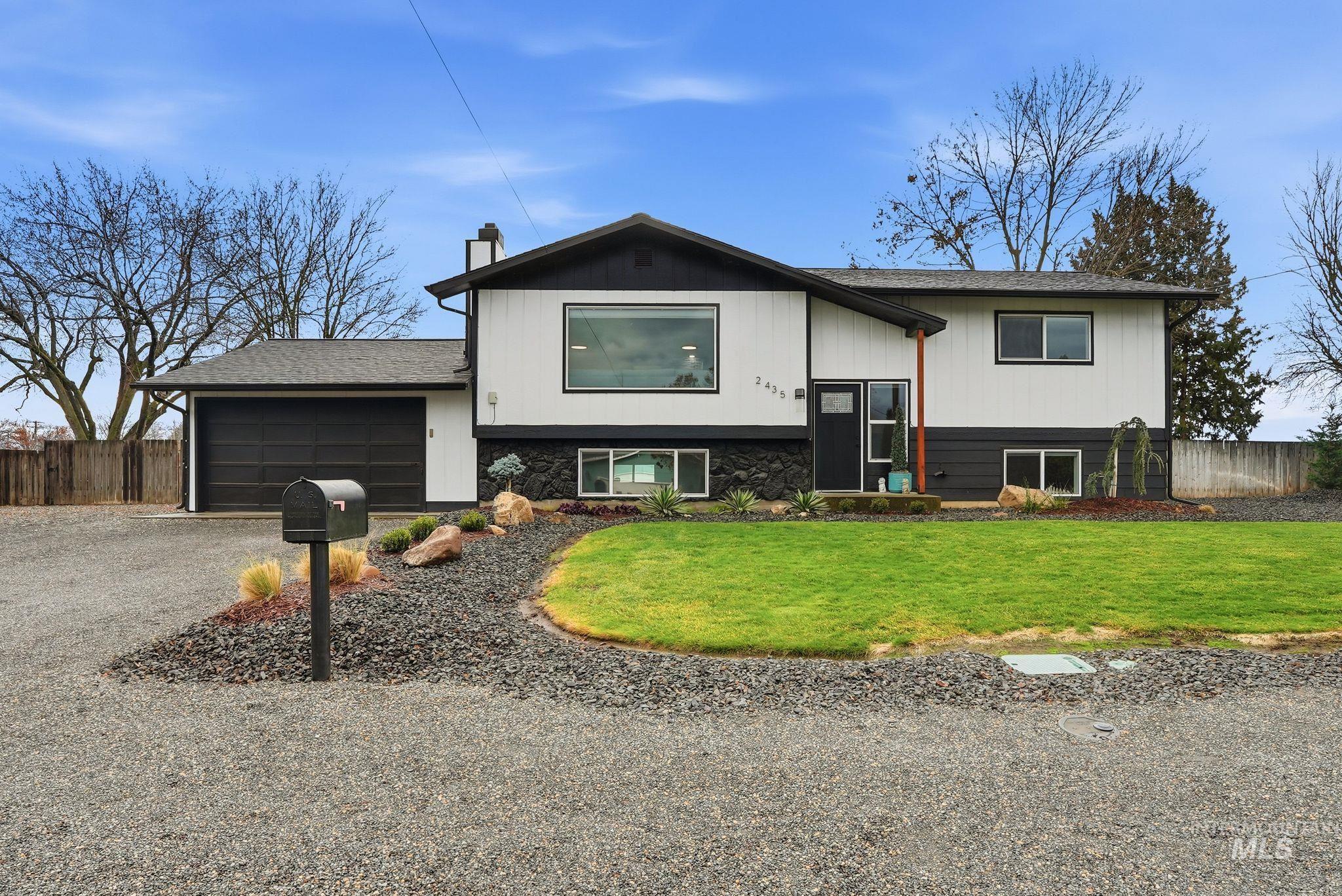 Raised ranch with driveway, a chimney, an attached garage, and roof with shingles