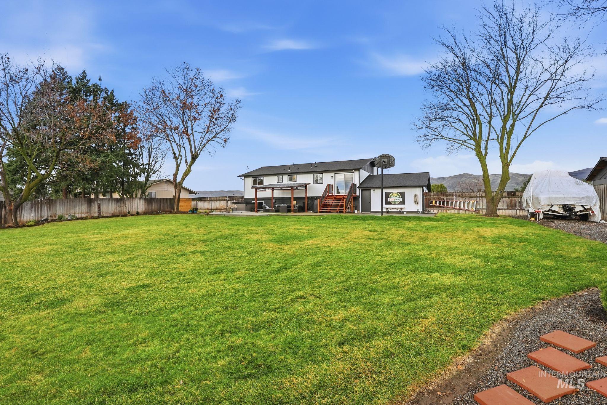 Back of property featuring a fenced backyard, stairs, an outdoor structure, and a patio