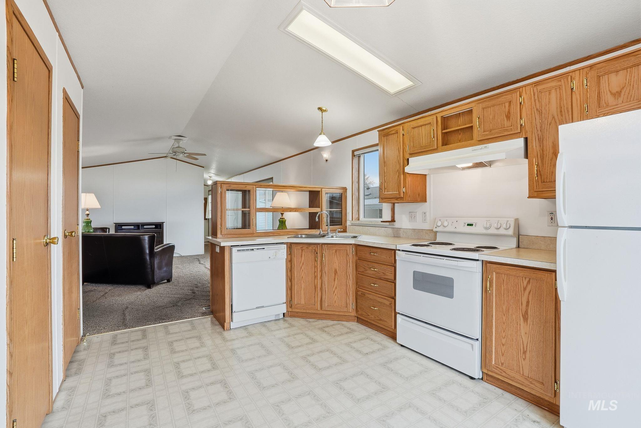 Kitchen featuring open shelves, light flooring, white appliances, lofted ceiling, and light countertops