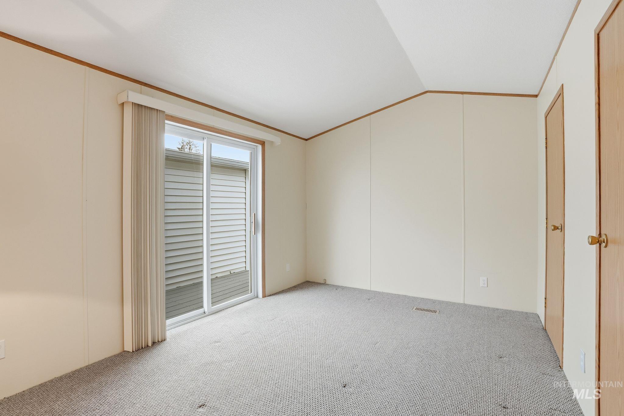 Unfurnished room with carpet, crown molding, a decorative wall, and lofted ceiling