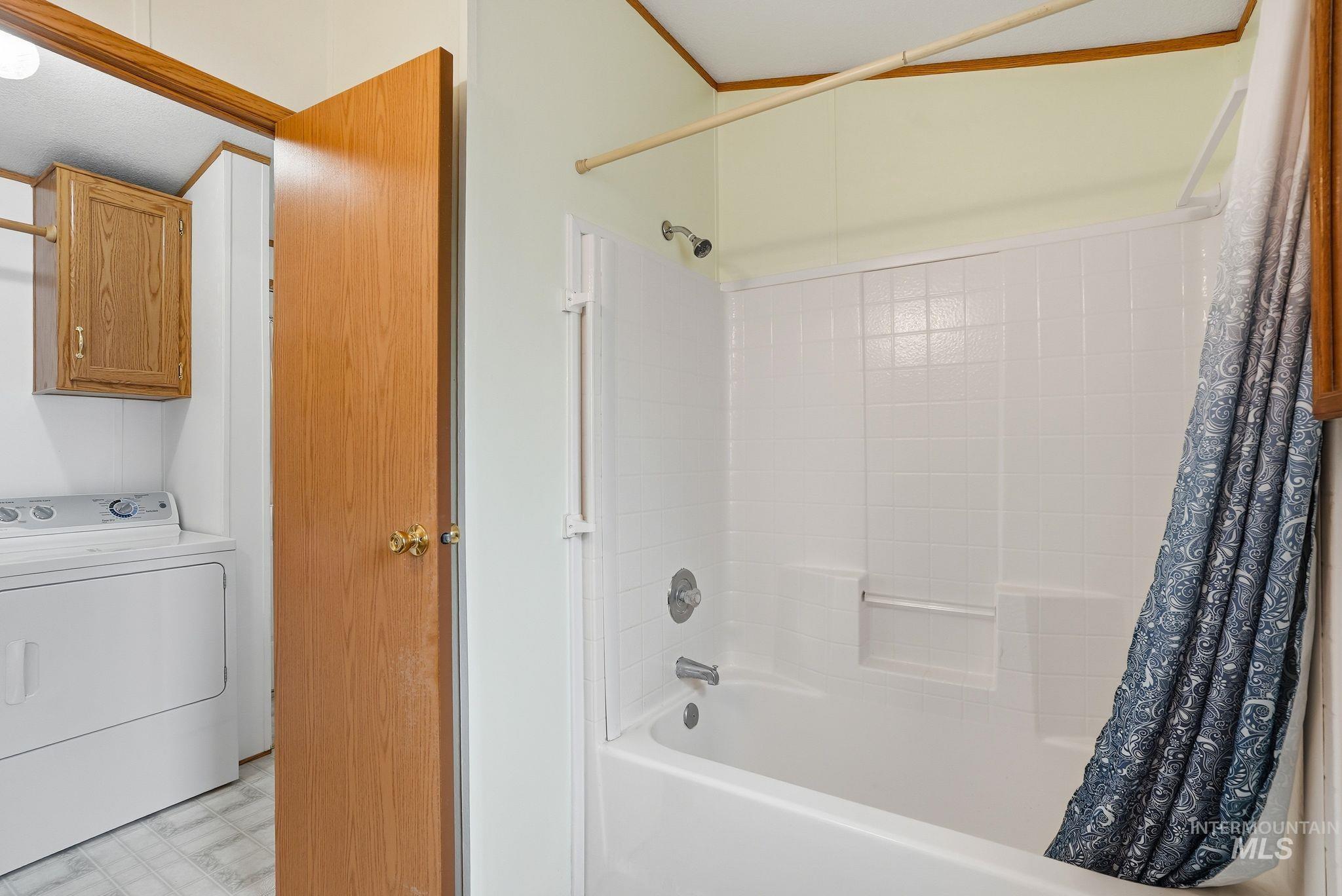 Full bath with washer / clothes dryer, shower / bathtub combination with curtain, and light flooring