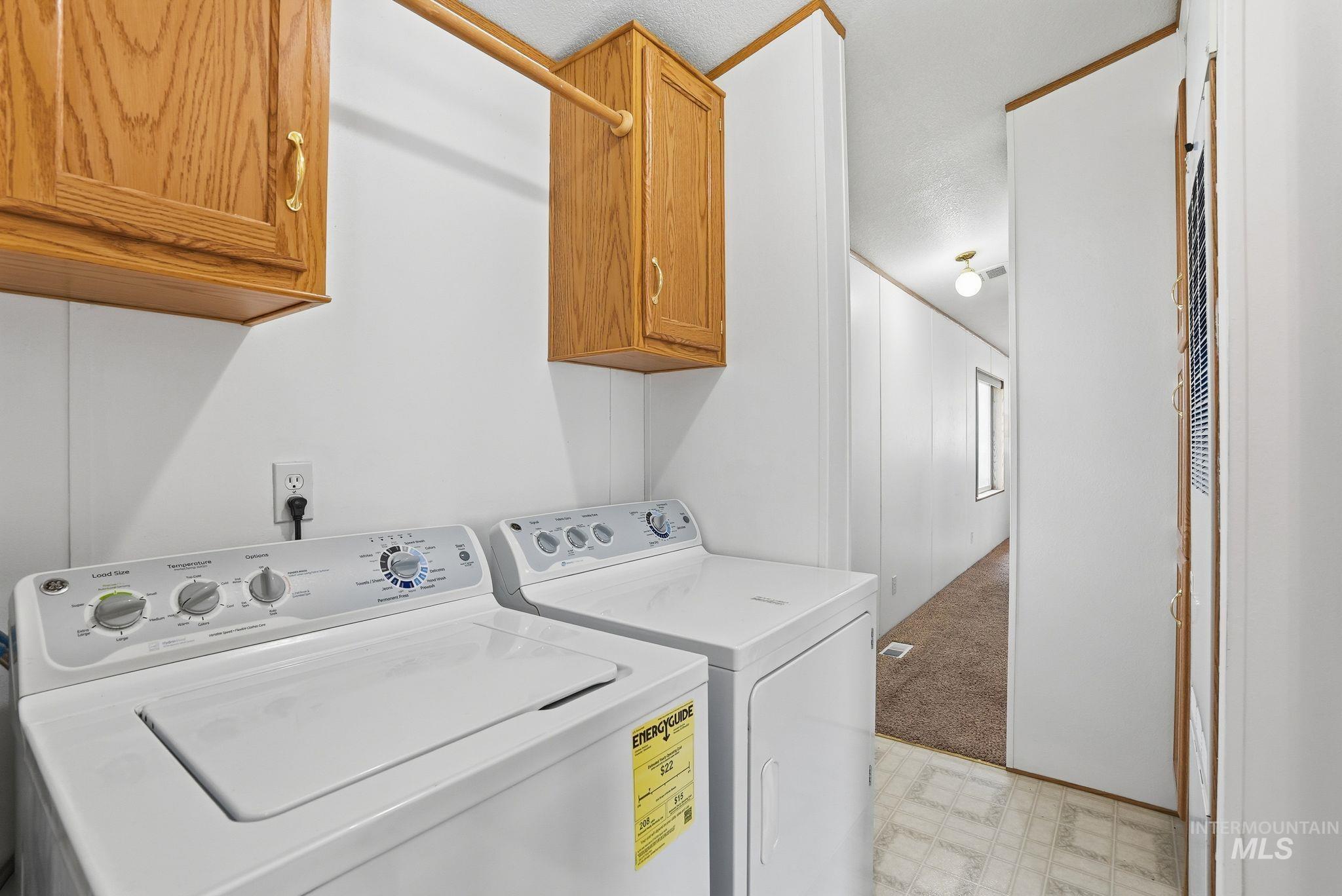 Laundry room featuring light flooring, cabinet space, and washing machine and clothes dryer
