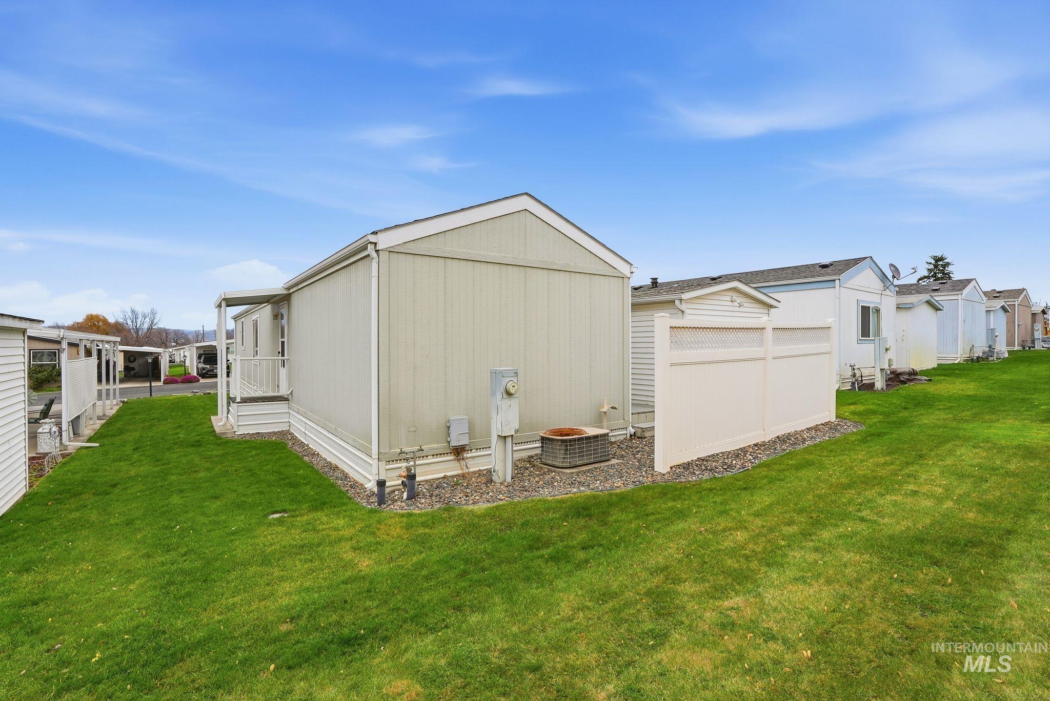 View of side of property with a yard and a cooling unit