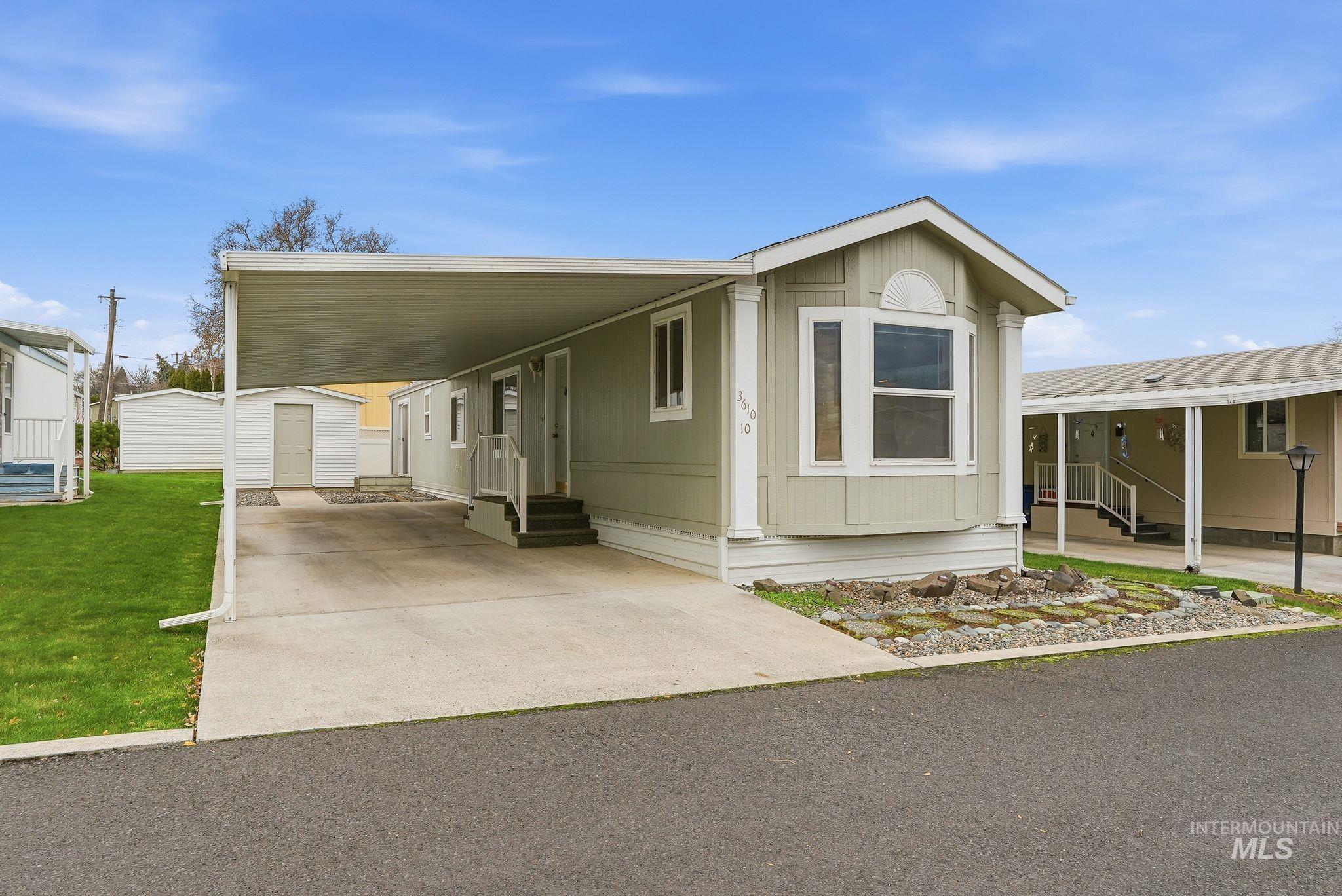 Manufactured / mobile home with entry steps, a carport, a shed, and concrete driveway