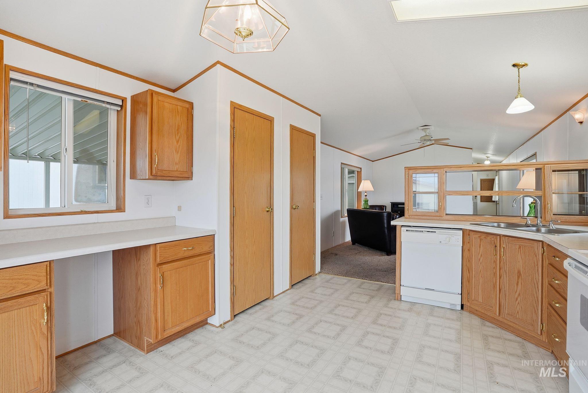 Kitchen with light flooring, vaulted ceiling, light countertops, white appliances, and pendant lighting