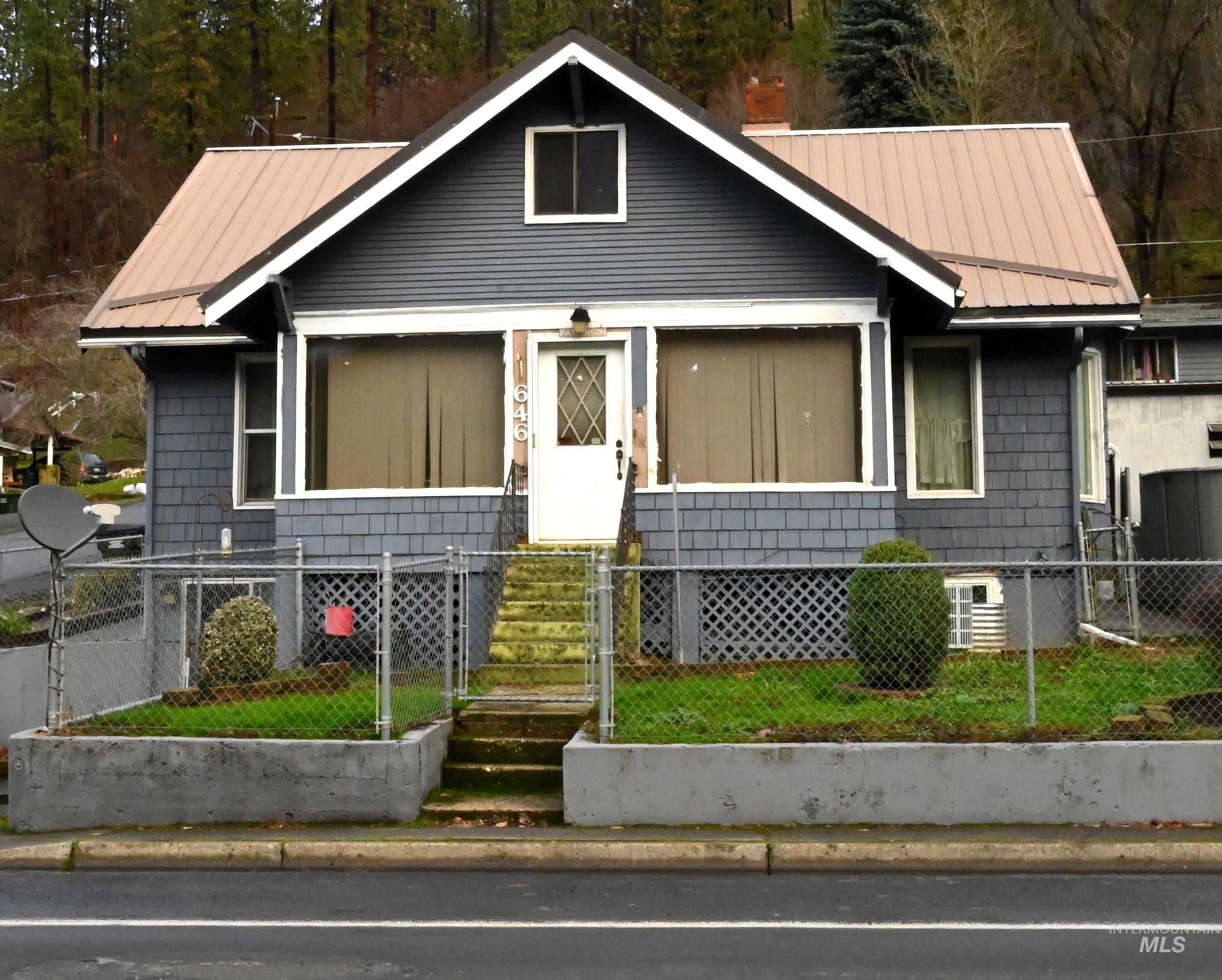 View of front of home with a gate, a metal roof, and a fenced front yard