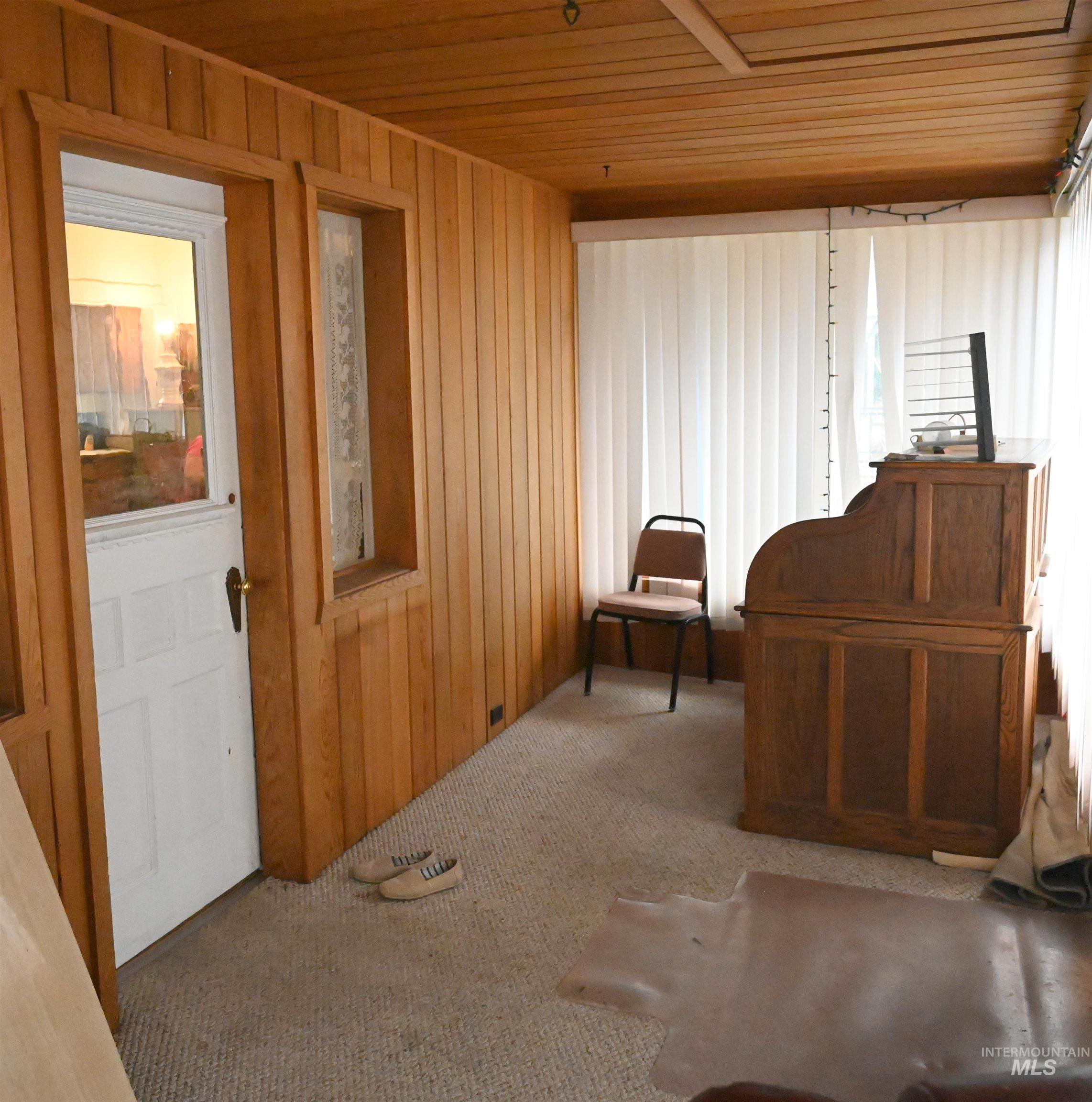 Sitting room featuring wood ceiling, carpet, and wooden walls