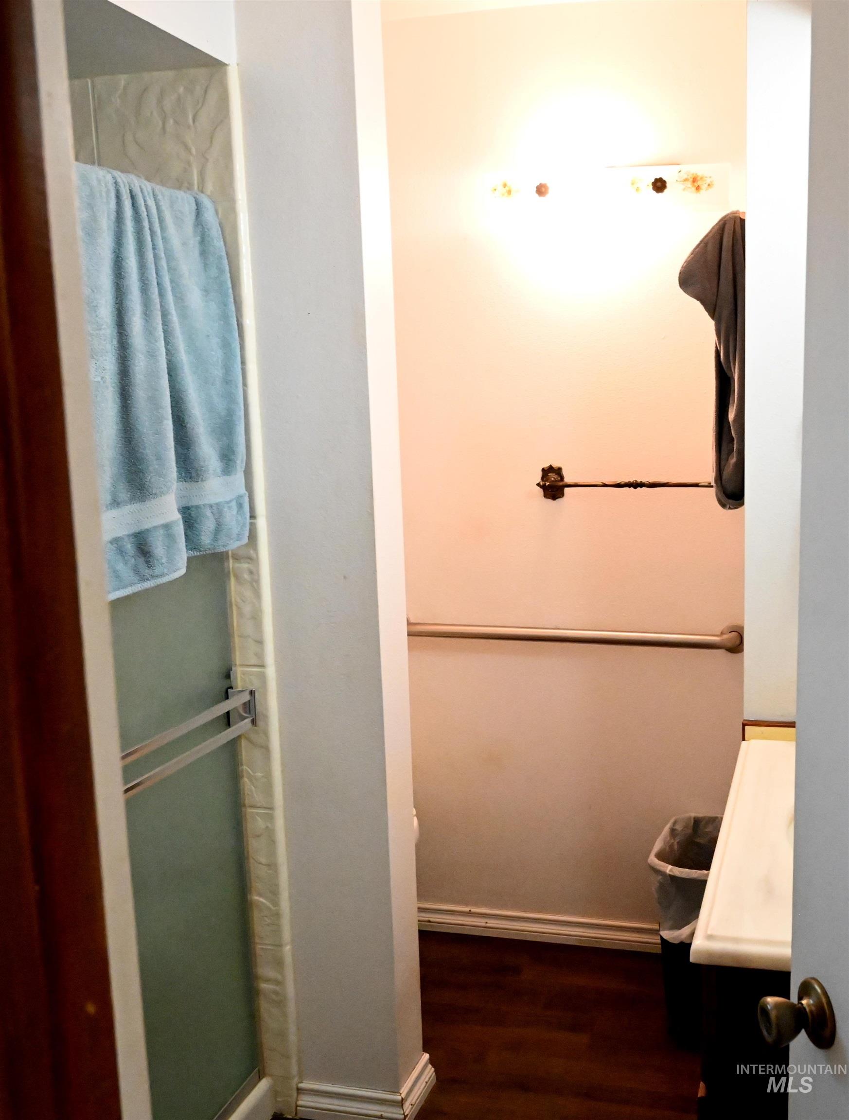 Bathroom with a shower stall, vanity, and dark wood-type flooring