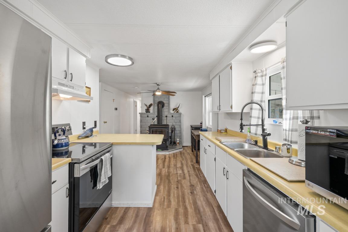 Kitchen with appliances with stainless steel finishes, light countertops, light wood finished floors, and white cabinets