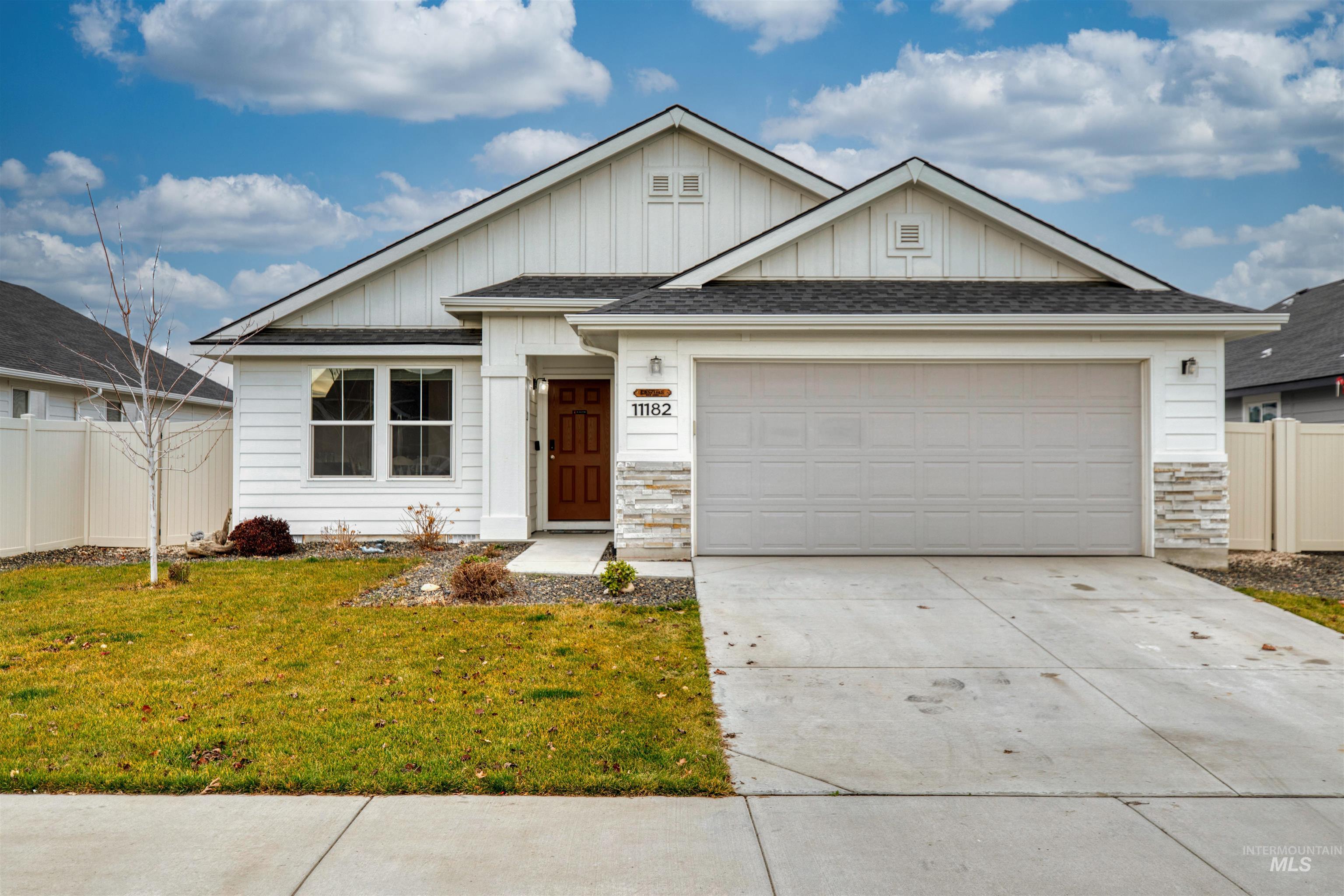 View of front of property with board and batten siding, roof with shingles, driveway, and a garage