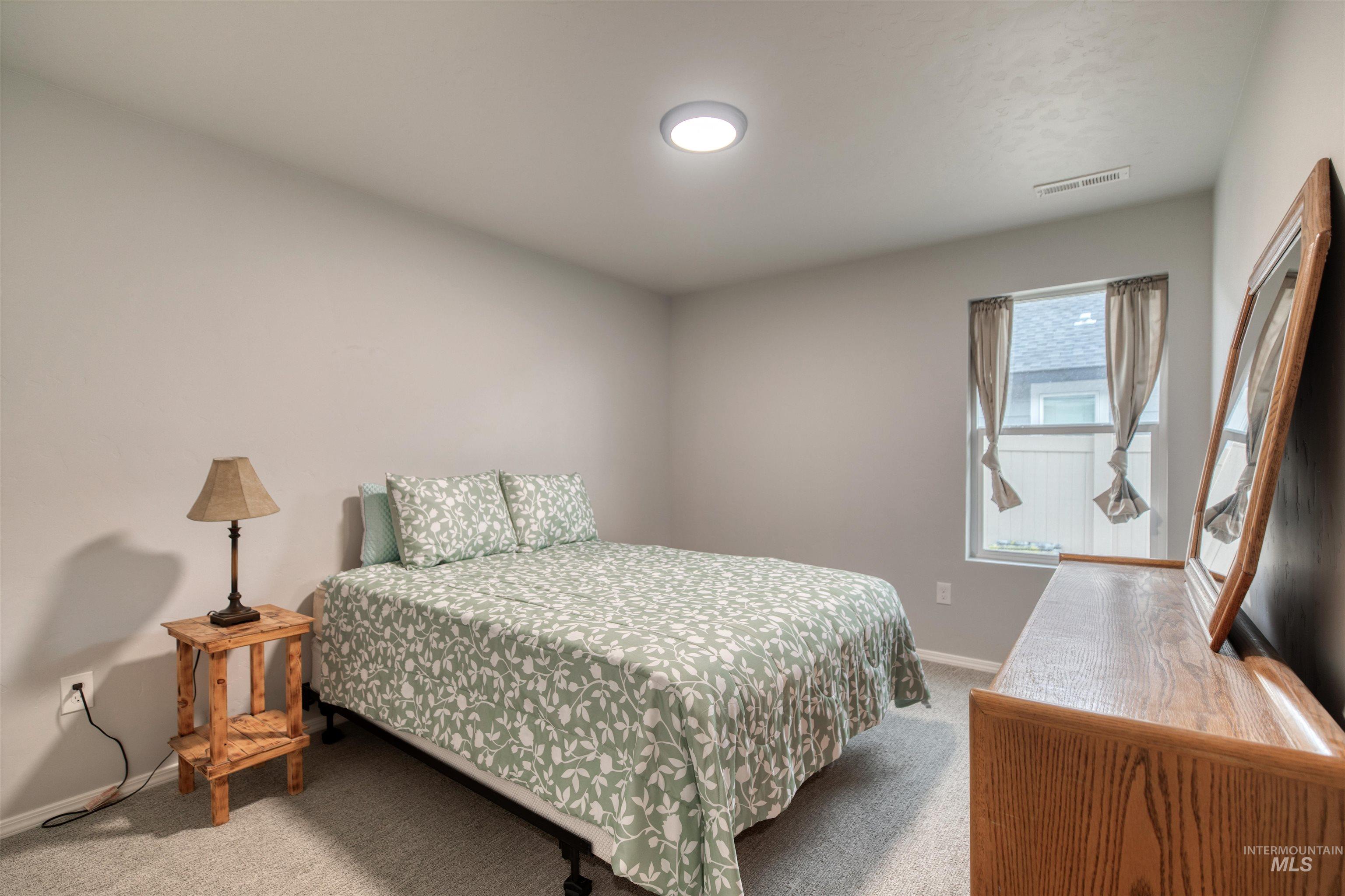 Bedroom featuring light carpet and baseboards
