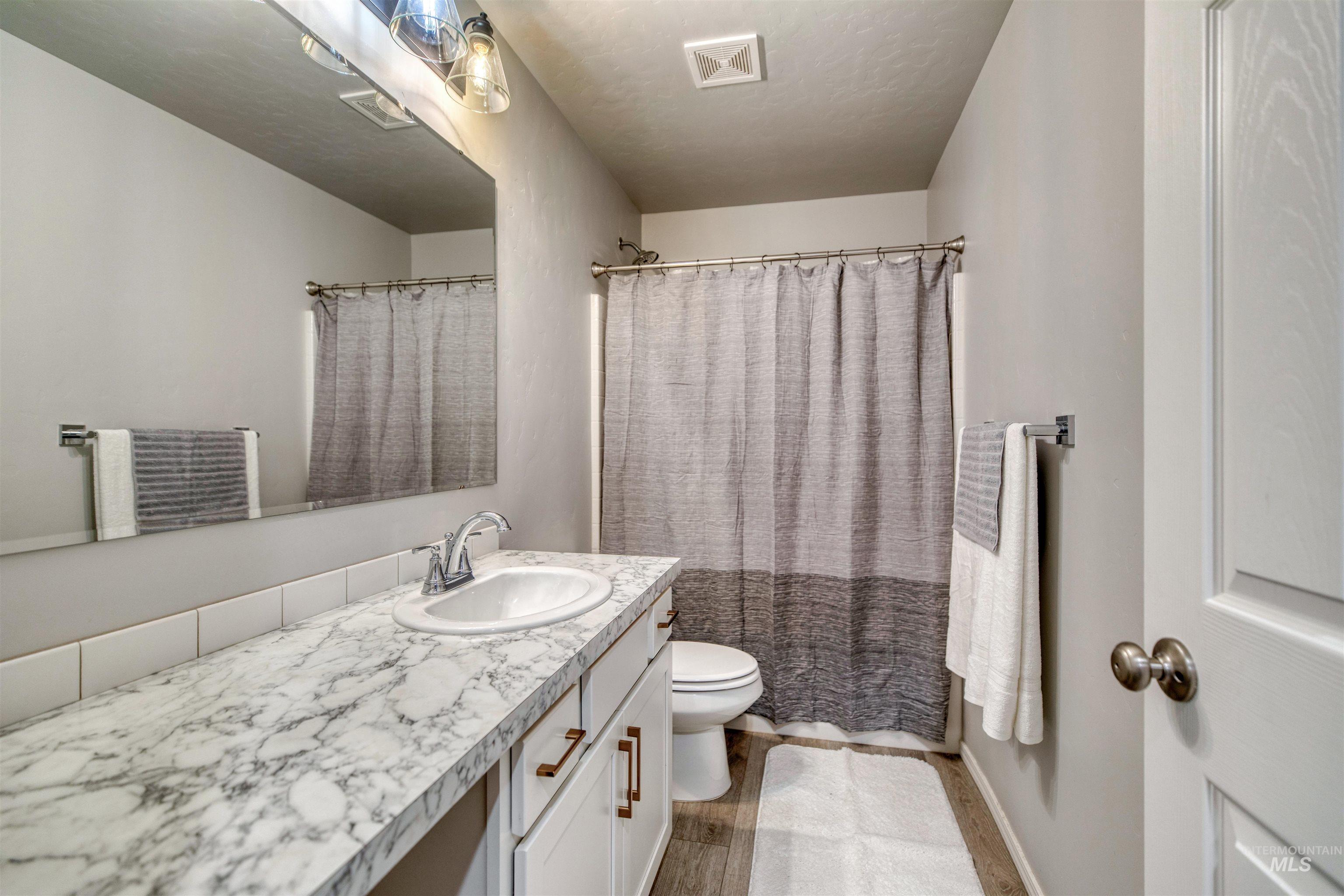 Bathroom with a shower with shower curtain, vanity, and dark wood finished floors