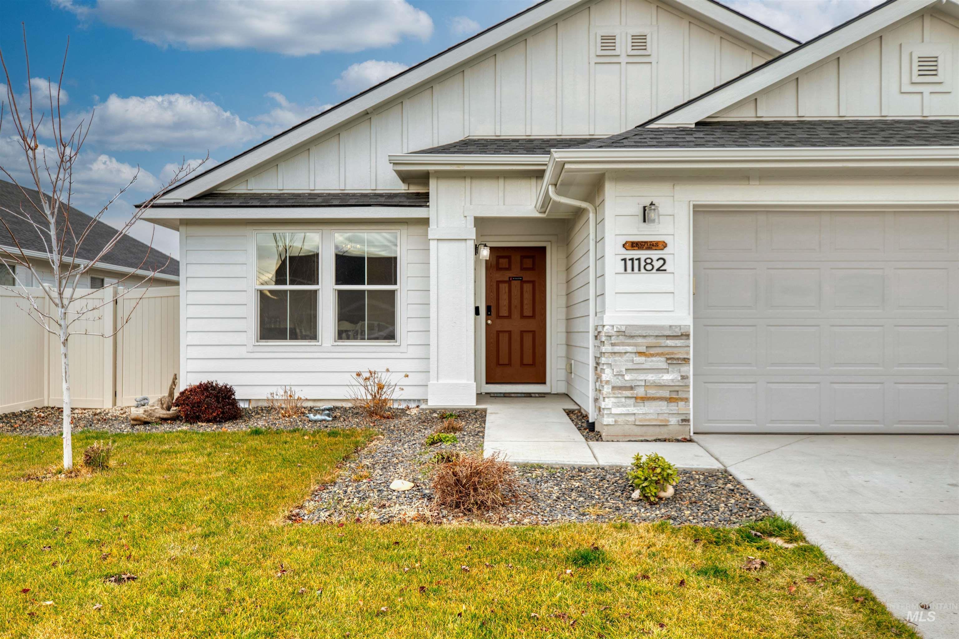 View of front of property featuring board and batten siding, roof with shingles, a garage, and driveway