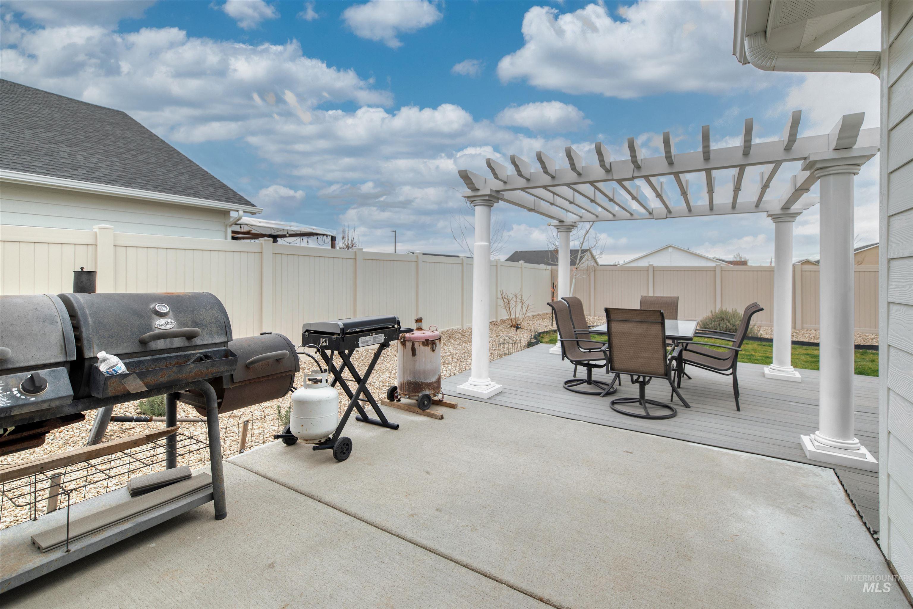 Fenced backyard featuring a patio area, a pergola, outdoor dining space, and area for grilling