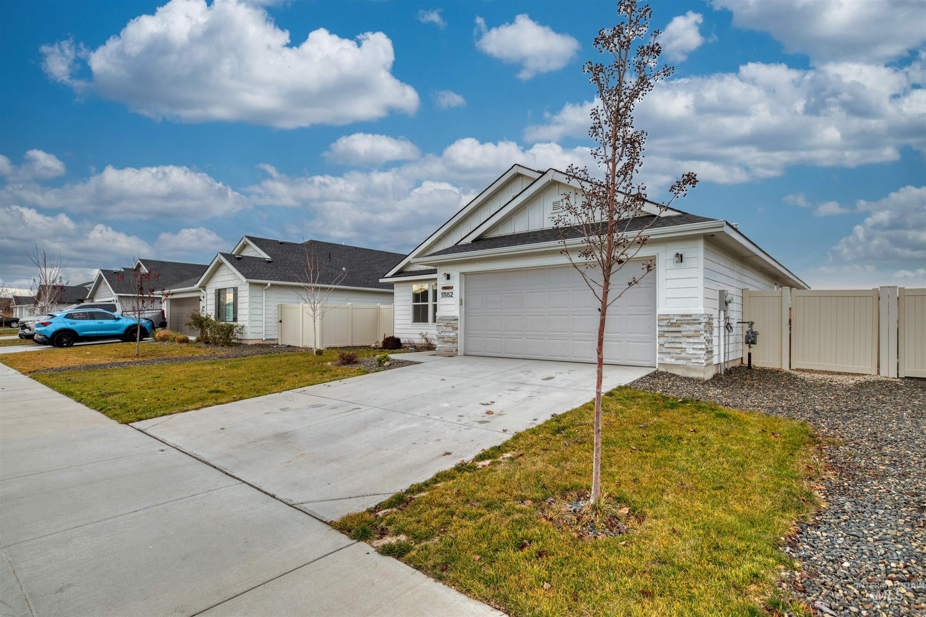 View of front of property with driveway, stone siding, a gate, and an attached garage