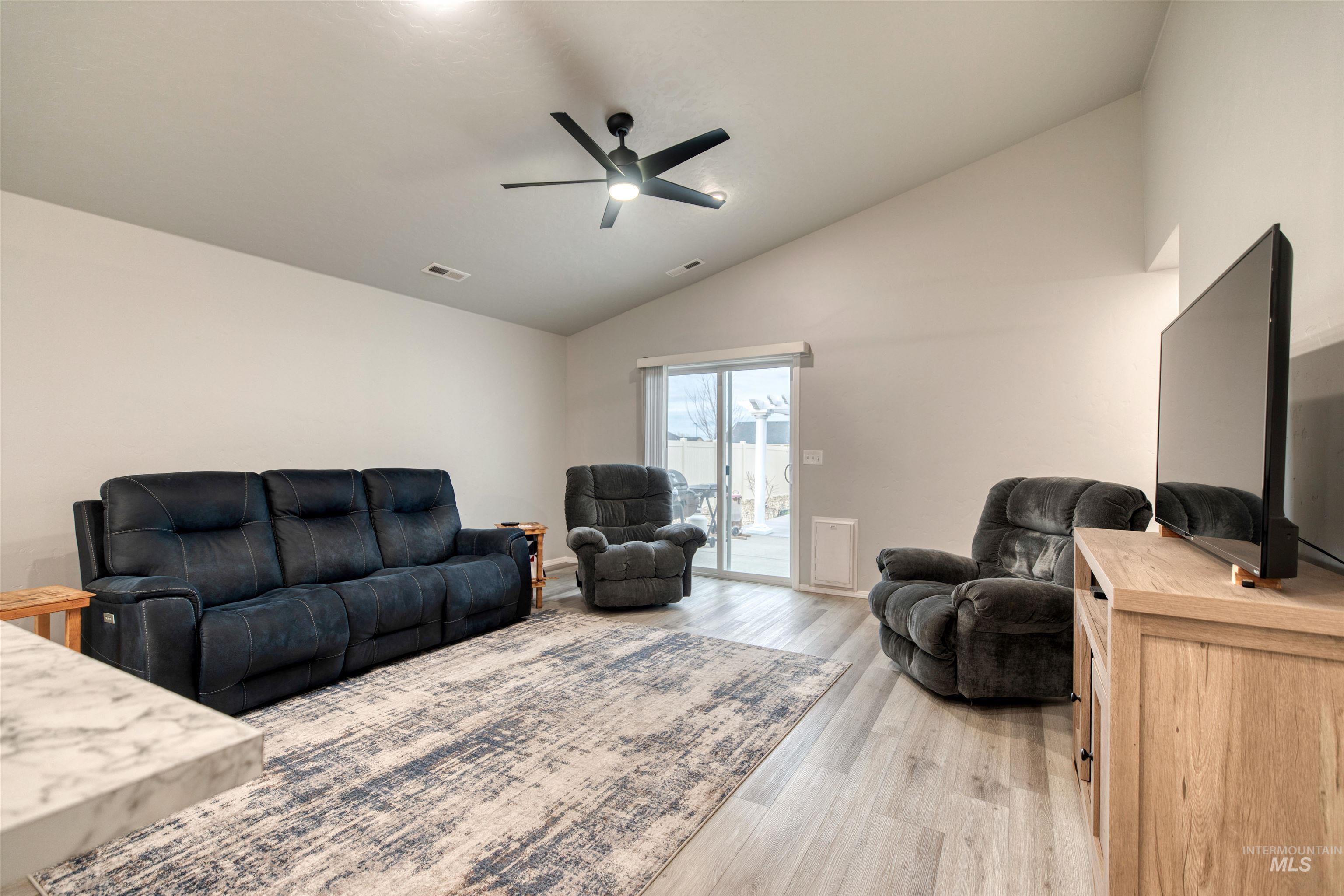 Living room featuring lofted ceiling, light wood-style floors, and a ceiling fan