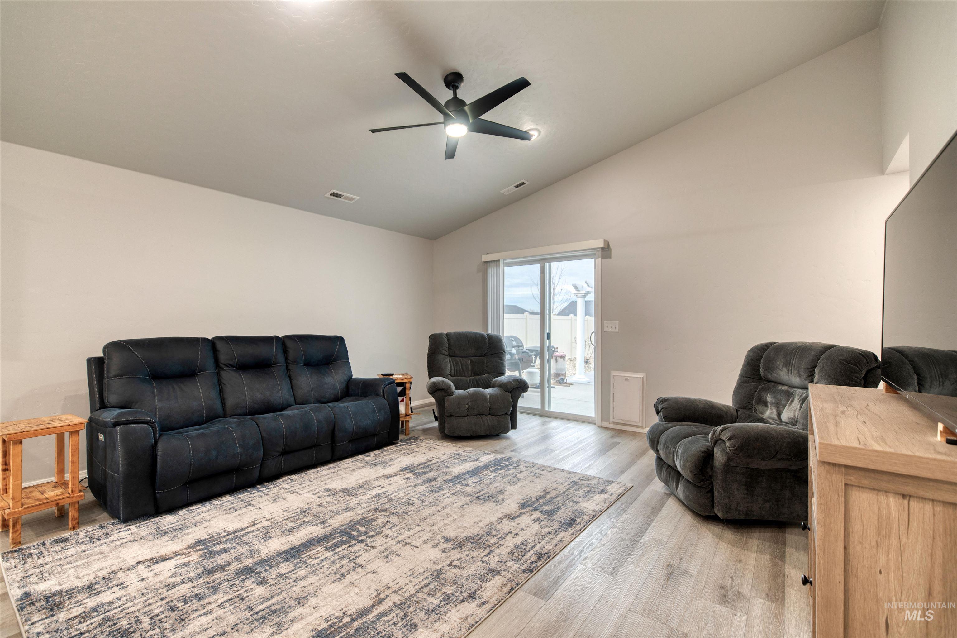 Living room featuring vaulted ceiling, light wood-style flooring, and a ceiling fan