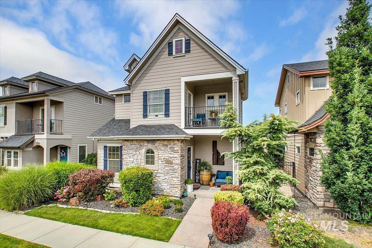 Traditional home featuring stone siding, a balcony, and a shingled roof