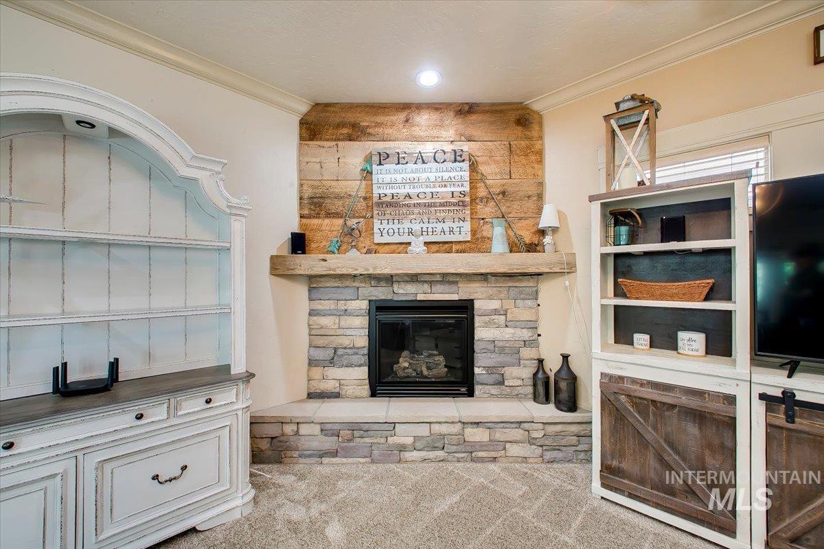 Unfurnished living room with ornamental molding, a fireplace, and carpet