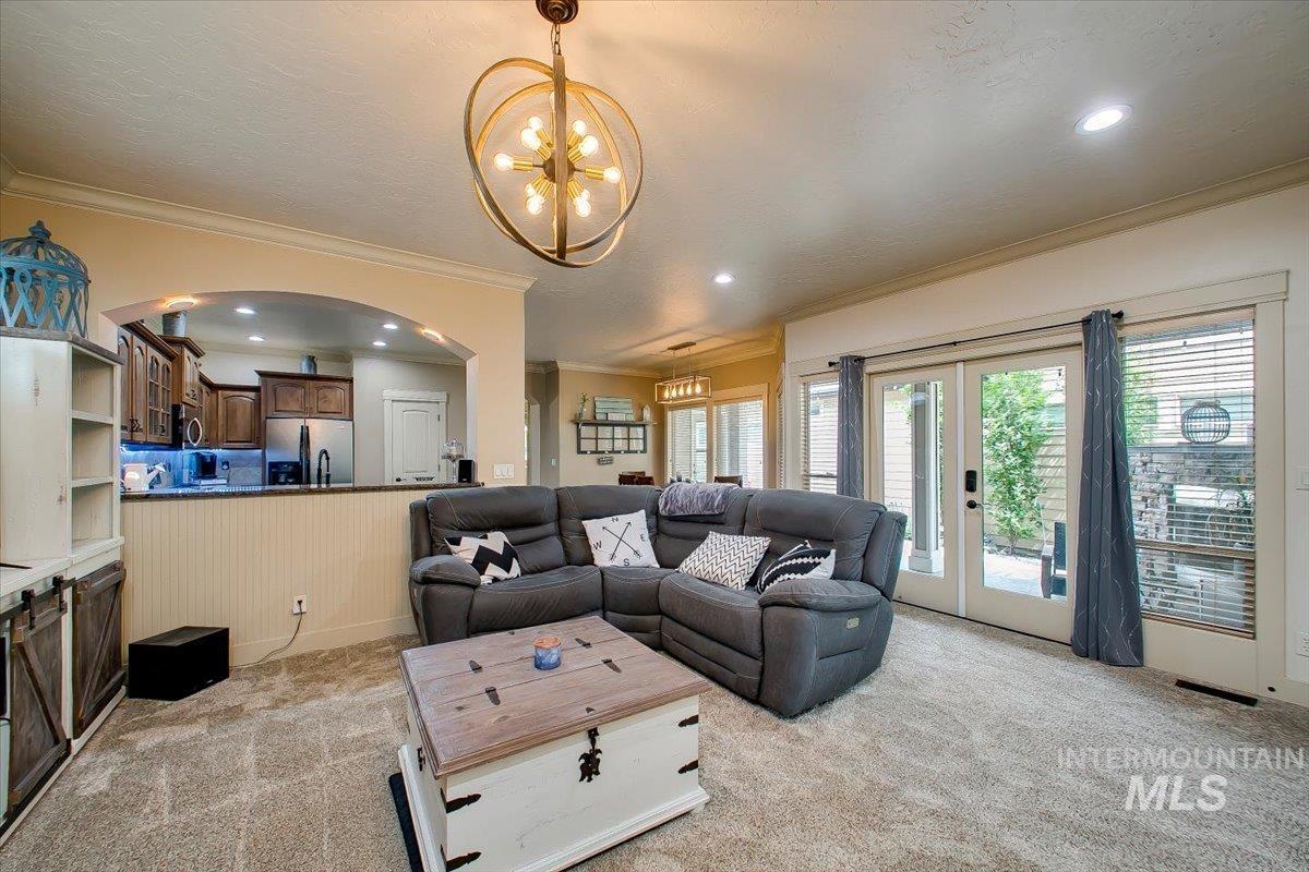 Living room with light carpet, crown molding, recessed lighting, and a chandelier