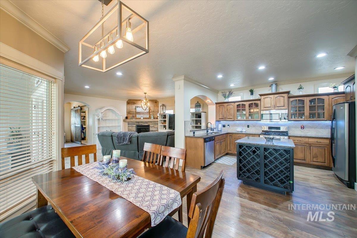 Dining space with arched walkways, crown molding, light wood-style floors, a fireplace, and a textured ceiling