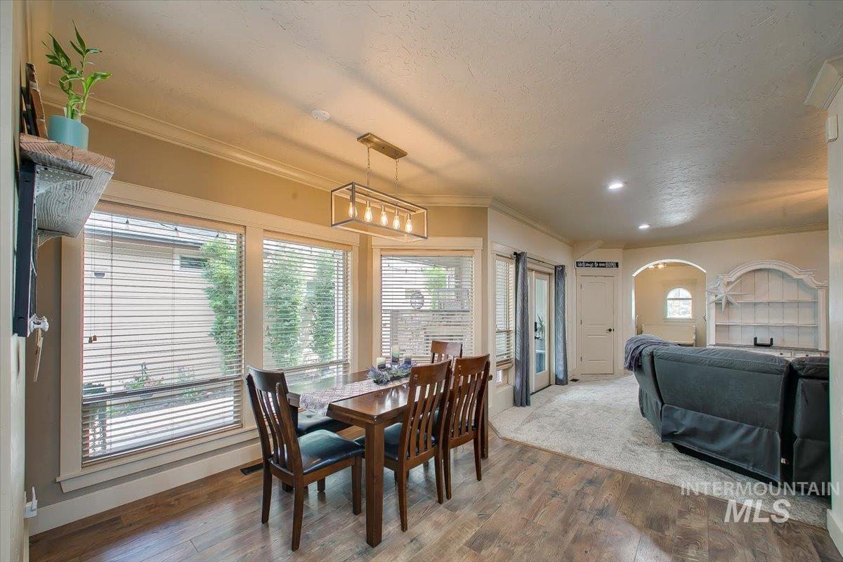 Dining room with ornamental molding, plenty of natural light, wood finished floors, a textured ceiling, and arched walkways
