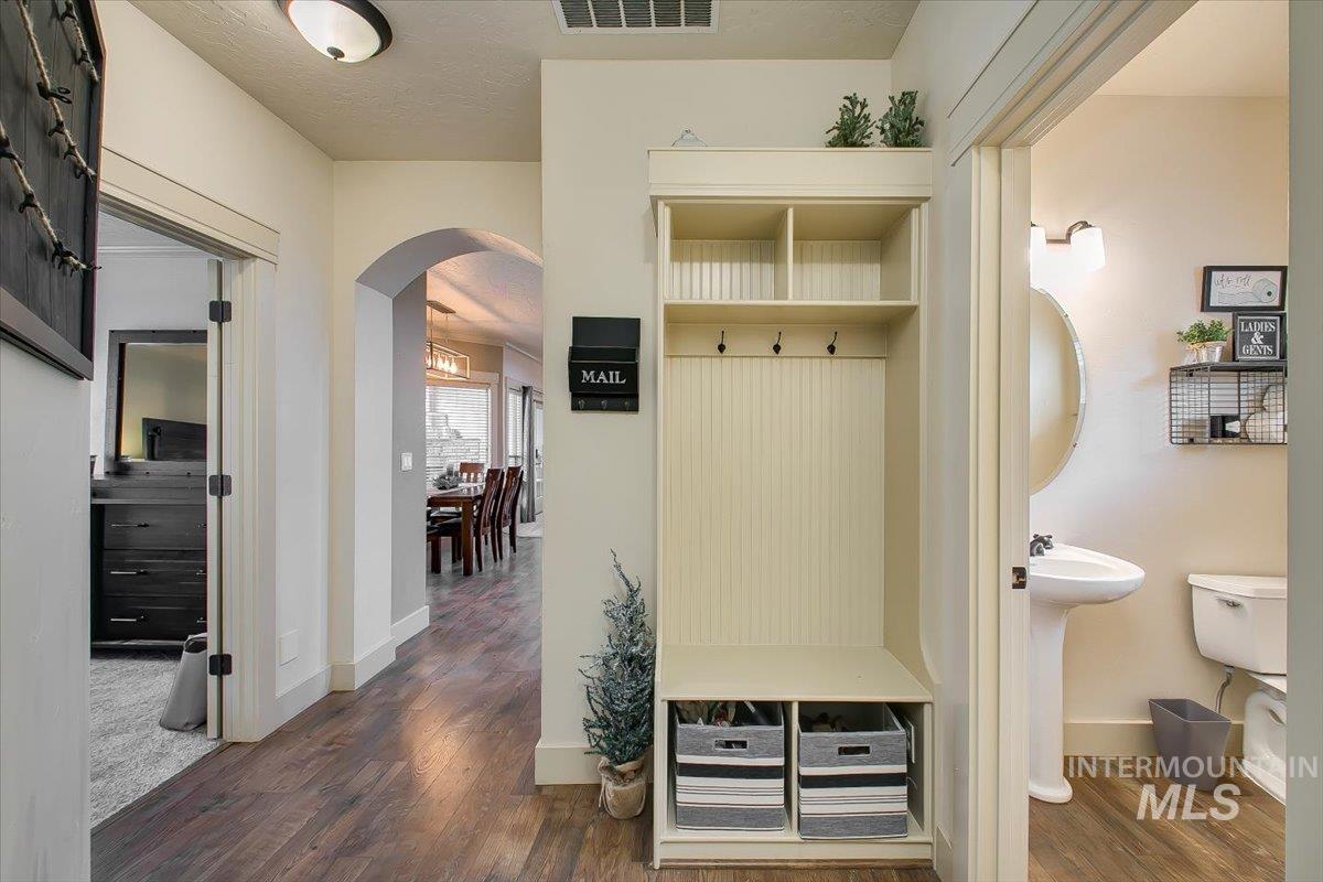 Mudroom with arched walkways, dark wood-style floors, and a textured ceiling