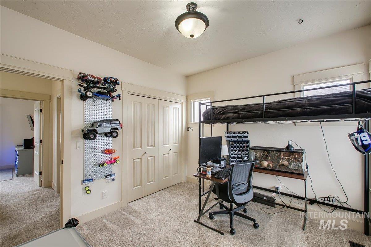 Bedroom featuring light colored carpet, an office area, and a closet