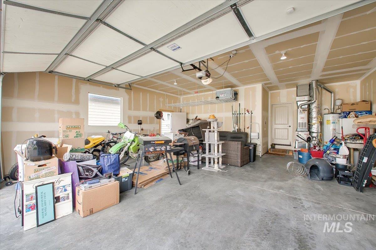 Garage featuring a heating unit, electric water heater, and heating unit