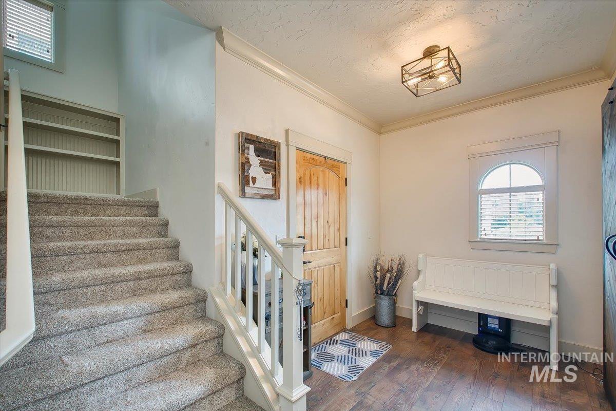Entryway with stairway, ornamental molding, dark wood finished floors, and a textured ceiling