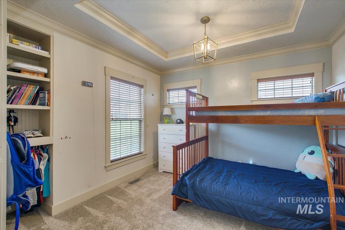 Bedroom featuring carpet, a tray ceiling, and crown molding