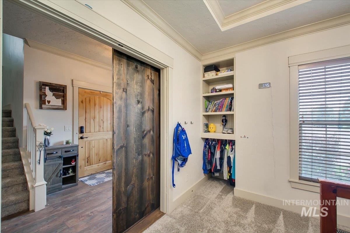 Interior space featuring ornamental molding, built in features, stairway, dark carpet, and a textured ceiling