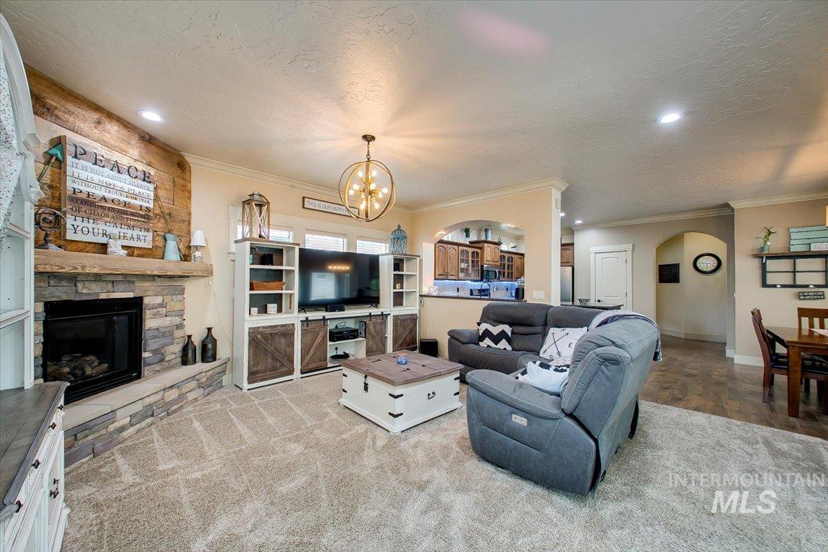 Living area featuring a fireplace, arched walkways, recessed lighting, a textured ceiling, and crown molding