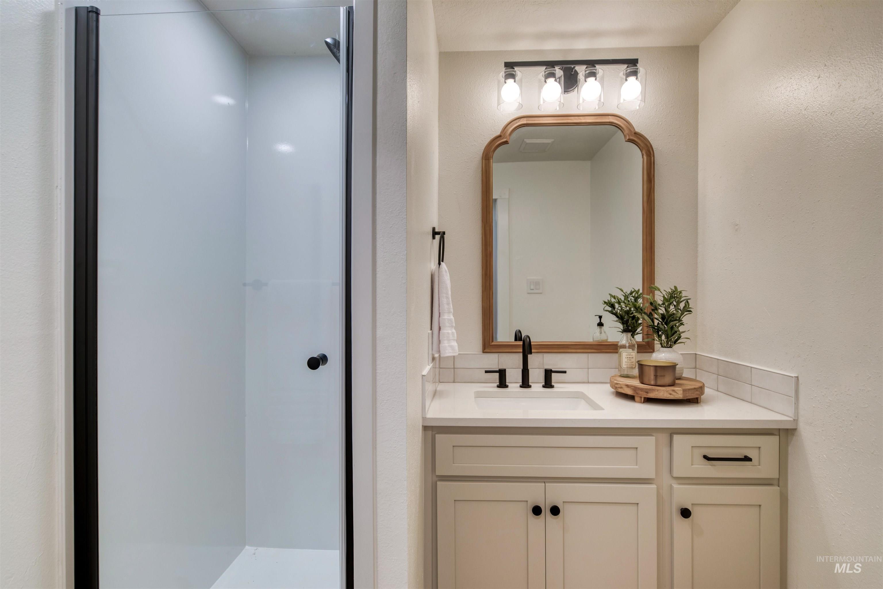 Bathroom featuring a textured wall, vanity, and a stall shower