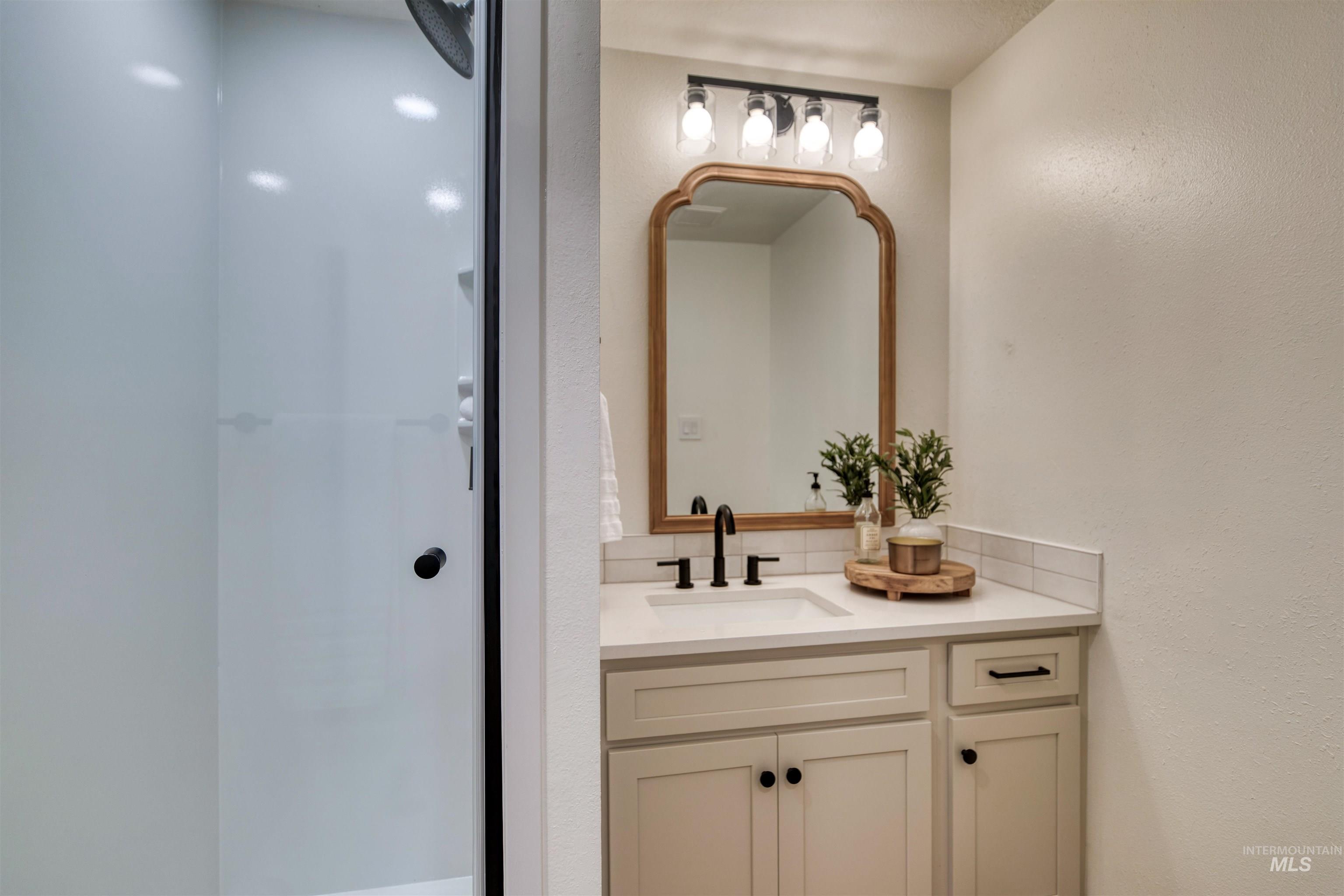 Full bath featuring vanity, a textured wall, and a shower