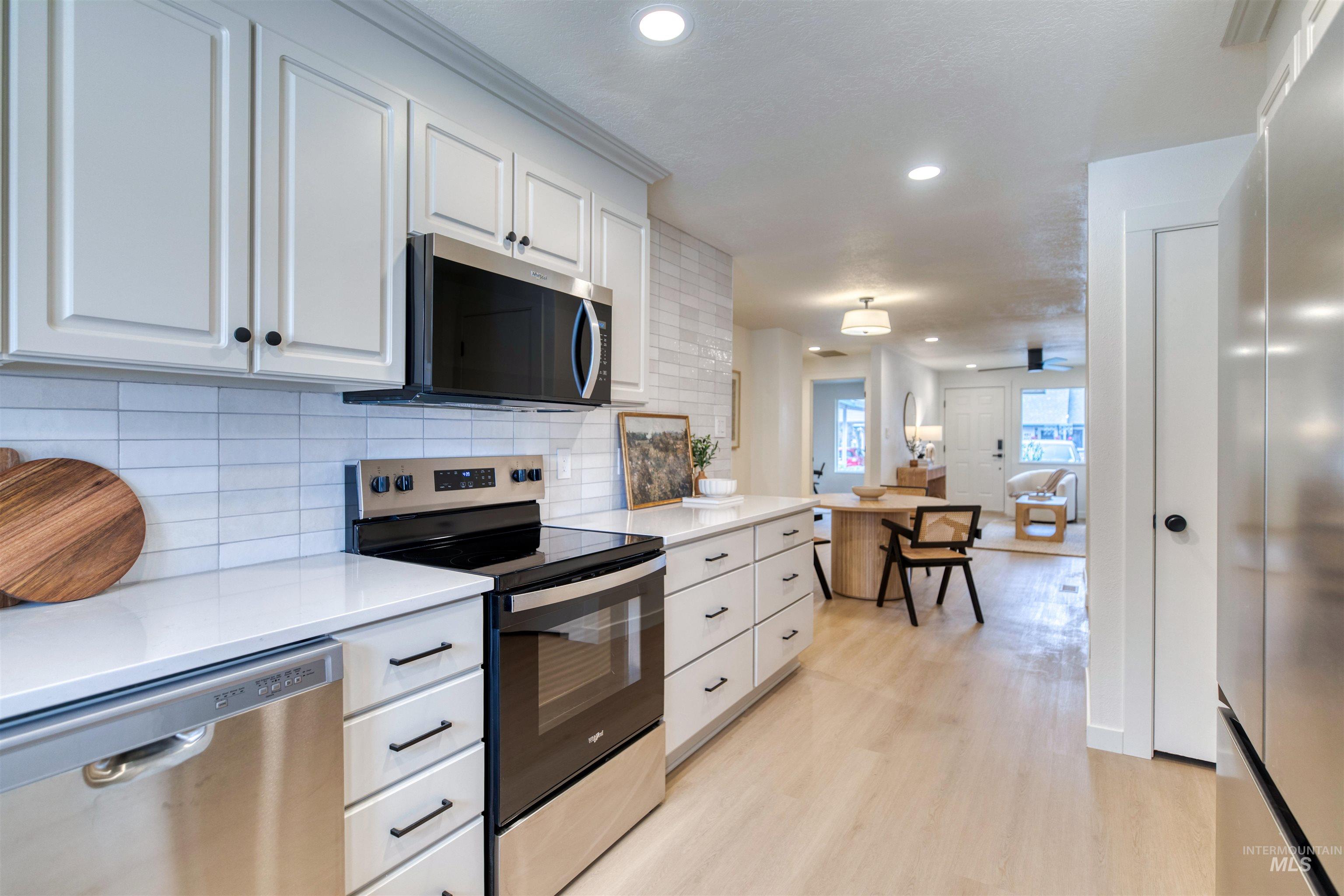 Kitchen featuring appliances with stainless steel finishes, white cabinets, recessed lighting, backsplash, and light wood finished floors