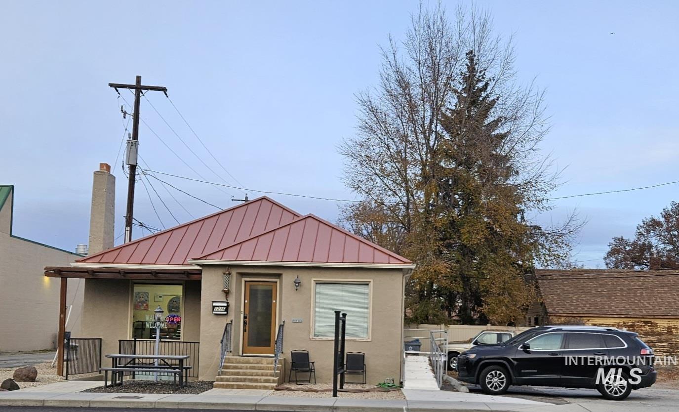 Bungalow featuring stucco siding, a standing seam roof, and a metal roof
