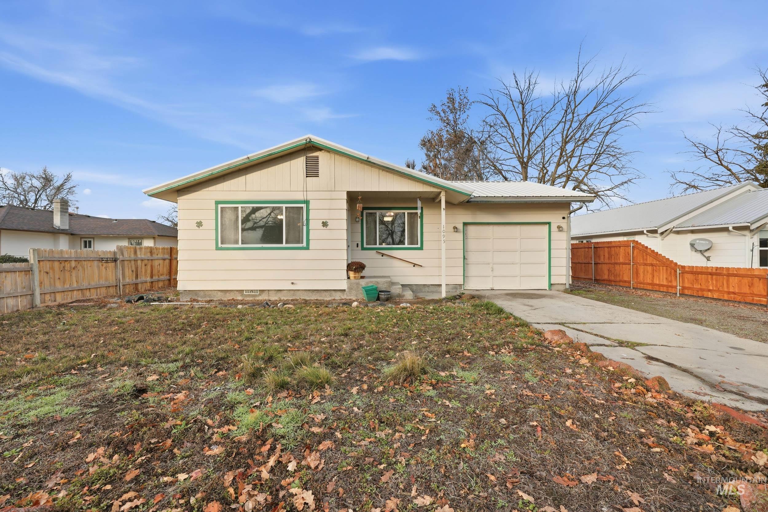 View of front of property featuring concrete driveway, a metal roof, and an attached garage