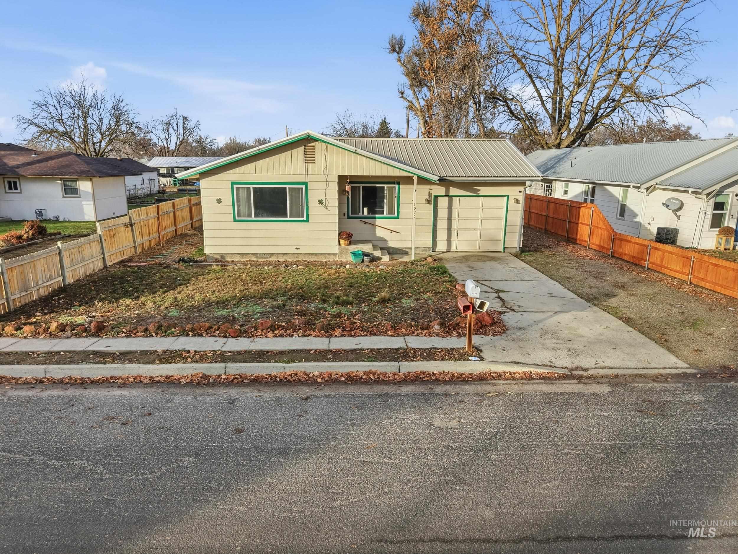 View of front of home featuring driveway, a metal roof, and a garage