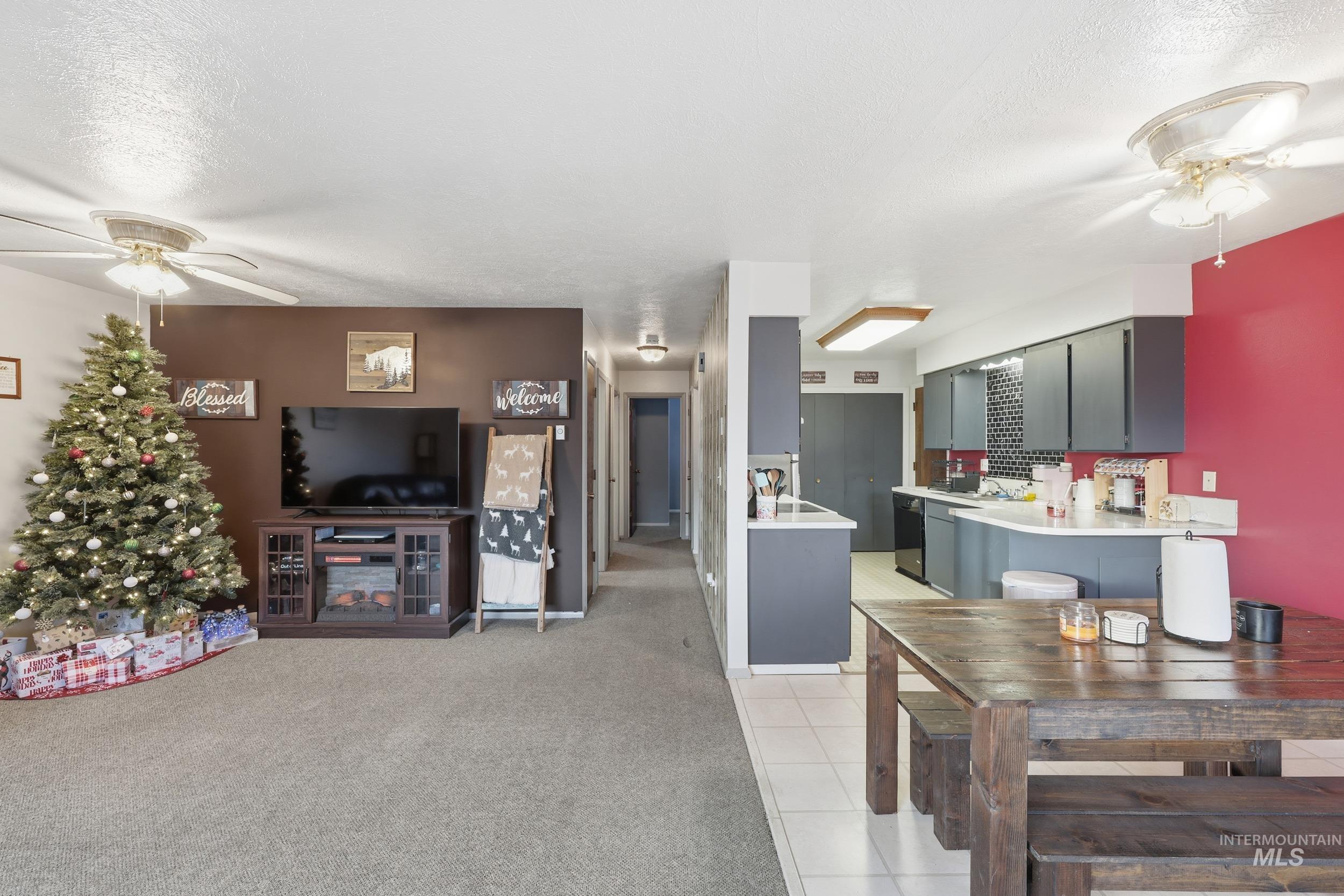 Living room featuring a ceiling fan, light carpet, a textured ceiling, and light tile patterned floors