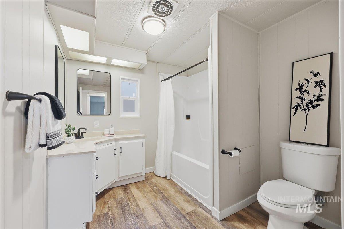 Full bathroom featuring vanity, light wood-style floors, and shower / tub combo with curtain
