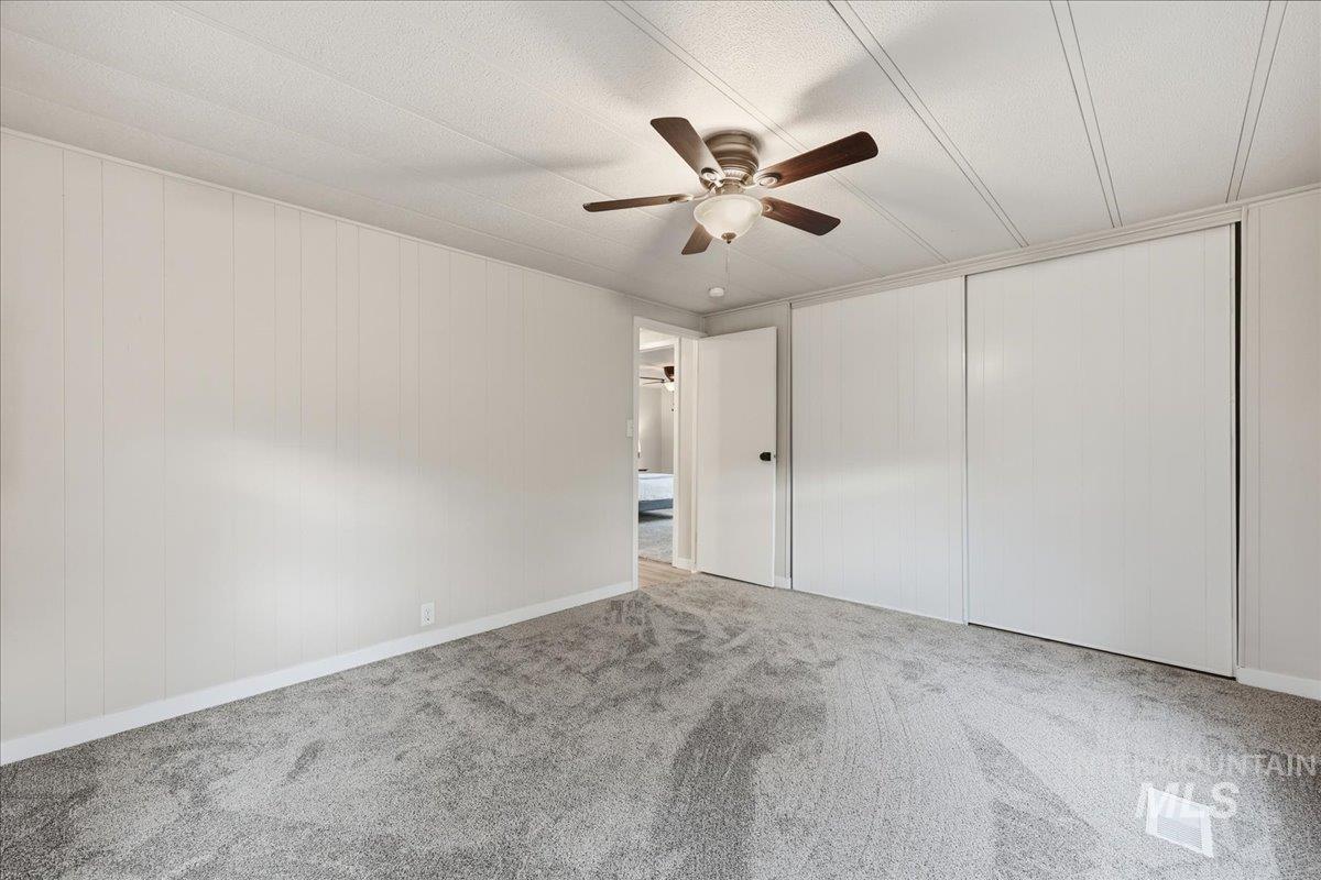 Spare room with ceiling fan, carpet, and wooden walls