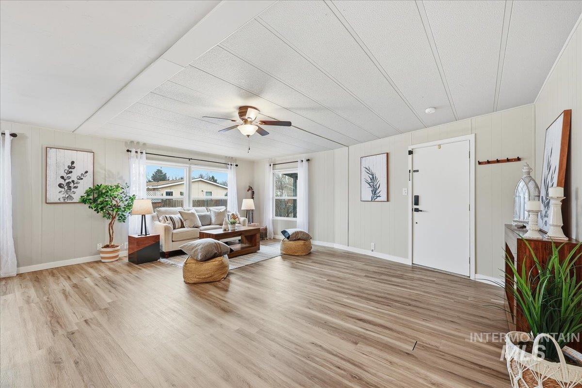 Living area featuring wood walls, light wood-type flooring, and a ceiling fan