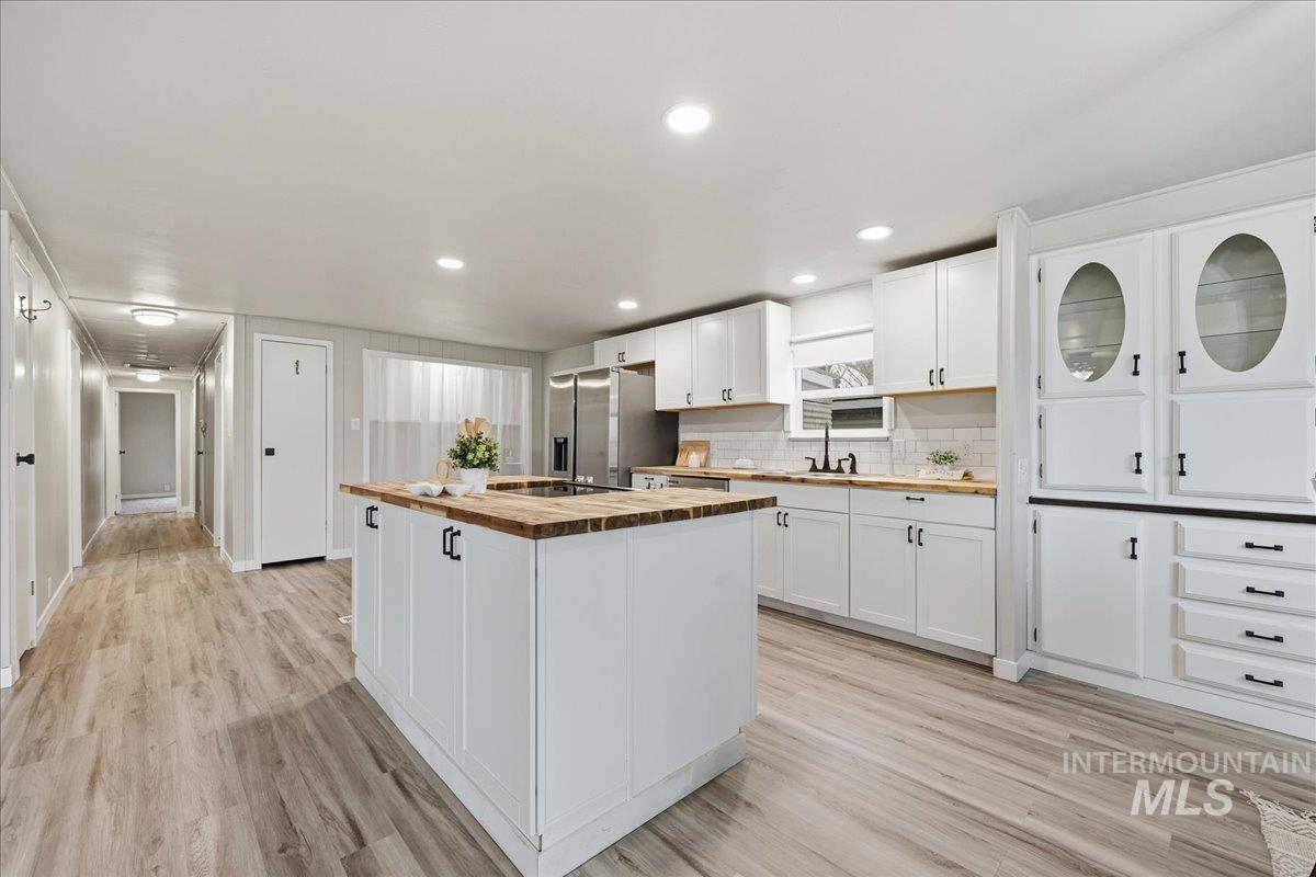Kitchen featuring white cabinetry, a center island, butcher block countertops, stainless steel fridge with ice dispenser, and recessed lighting